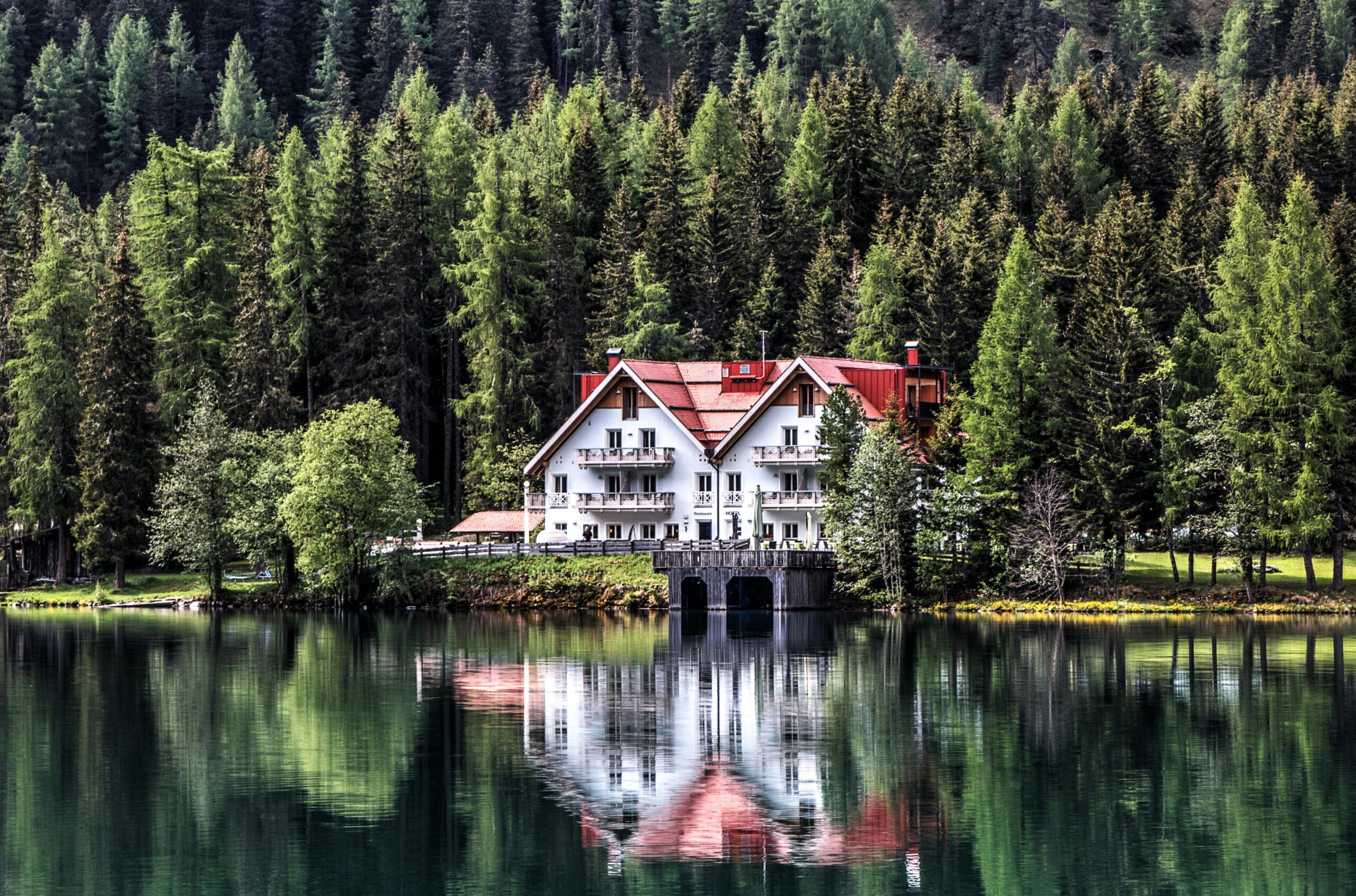 Charming chalet nestled by a serene lake with lush forest backdrop, showcasing perfect reflection. Ideal for nature lovers.