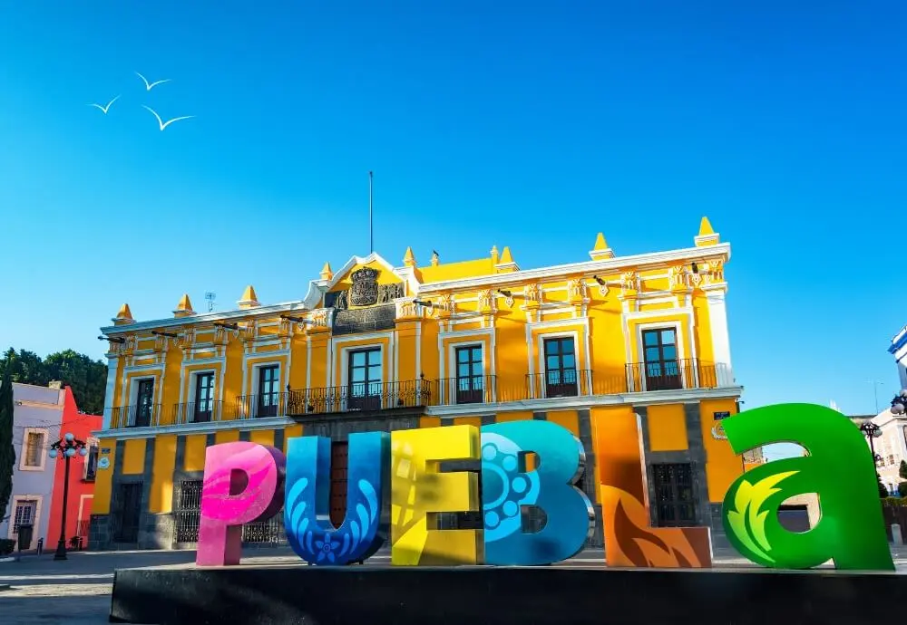 best-places-to-visit-in-Mexico-puebla-colorful-sign-with-yellow-colonial-building-in-mexico